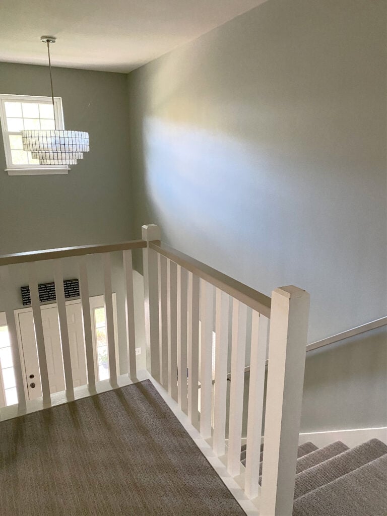 Staircase with white railing, beige taupe carpet and Sherwin Williams Austere Gray, best green gray paint color on the walls