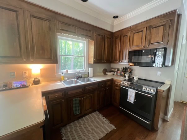 before update, kitchen with dark wood, maybe pine stained brown cabinets, oak floor, off-white laminate countertop