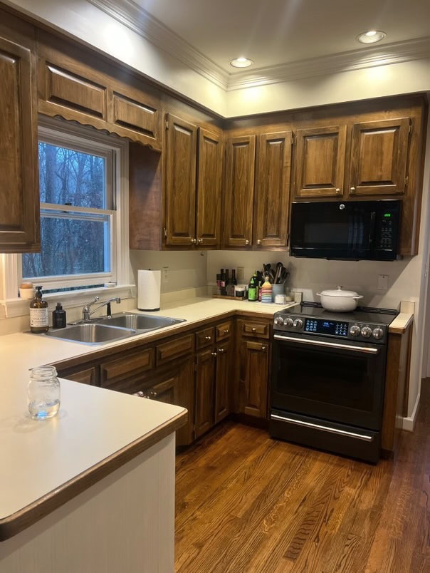 before update, kitchen with oak wood flooring, off-white laminate countertop, dark stained wood maybe pine cabinets