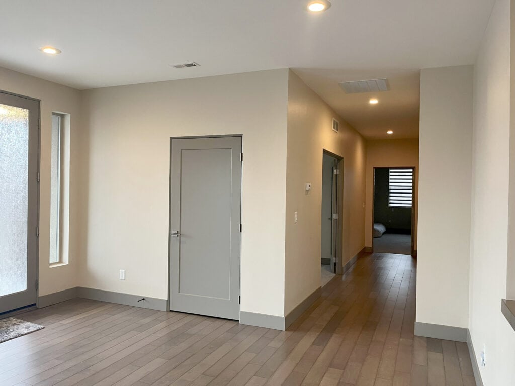 BEFORE EDESIGN off-white beige walls with greige, warm gray trim and doors, gray wash wood floor in entryway and dark hallway