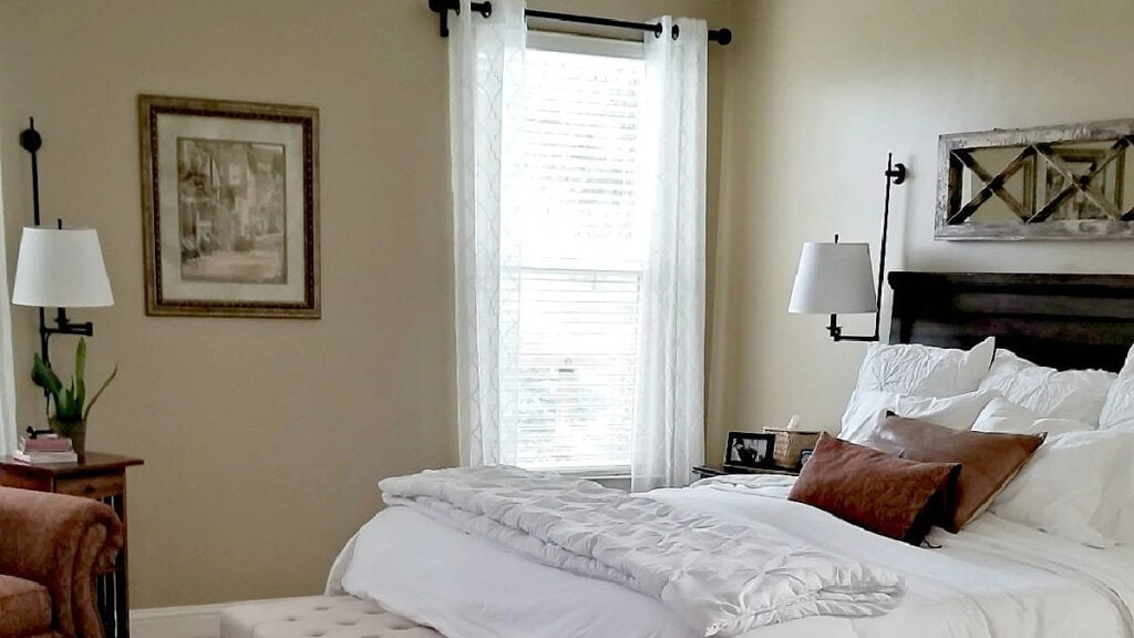 Benjamin Moore Lenox Tan in a bedroom with neutral bed linens, windows