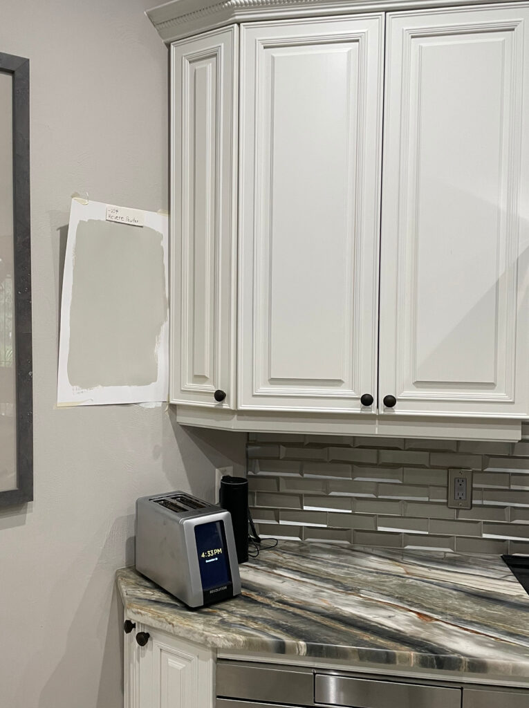 Benjamin Moore Revere Pewter paint sample with Icicle painted cabinets, quartzite countertop, metallic backsplash tile