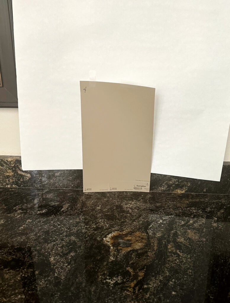 Black granite with gold veins, maybe Titanium Black, Black Fusion or Alair. Sherwin Williams Tony Taupe samplize peel and stick sample for cabinets