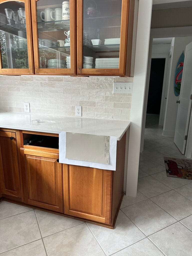Calacatta Gold white quartz countertop with 2000s beige tile and zellige look subway tile backsplash on cherry cabinets, Versatile Gray sample