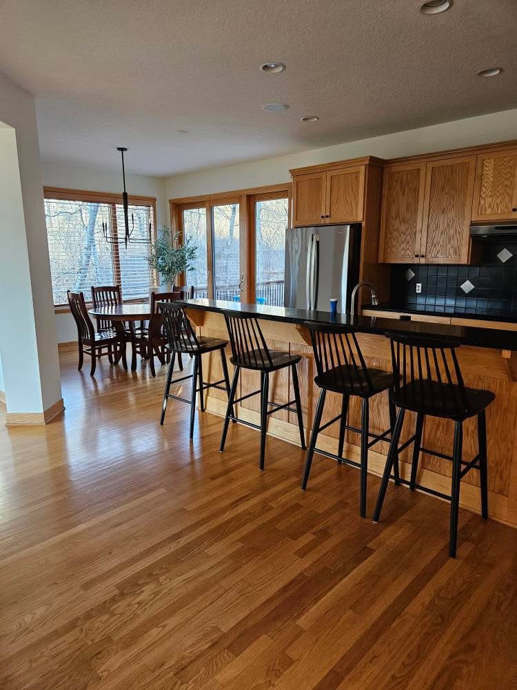 Oak wood kitchen cabinets with golden oak floor, black granite countertop, eating nook with wood trim