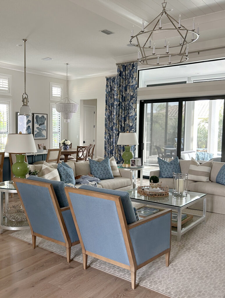 Open concept living room blue blue accent chairs, patterned drapes, PPG Paraffin warm neutral walls, Delicate white trim, black window, area rug, home decor