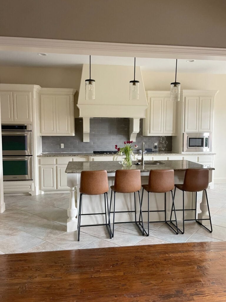 Sherwin Williams Casa Blanca cream painted kitchen wood cabinets, granite countertop, cool tile backsplash