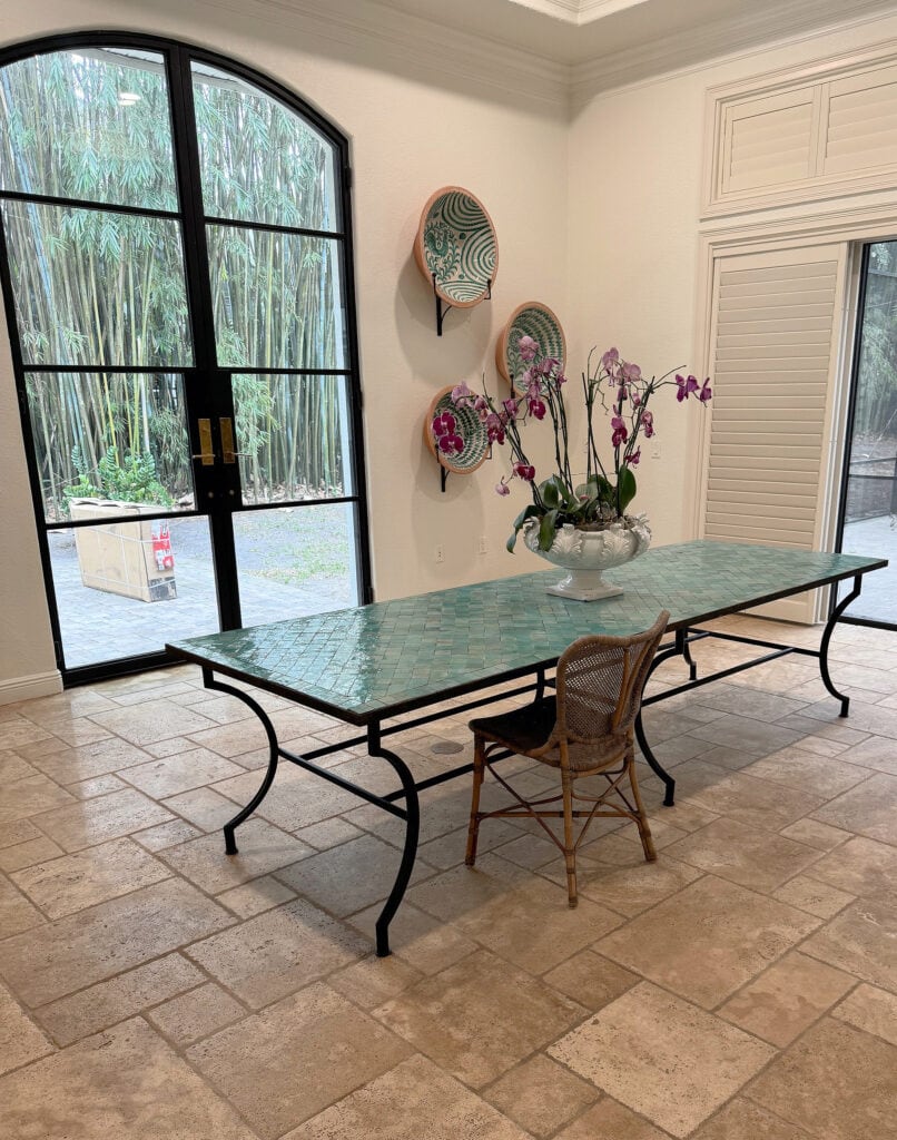 Sherwin Williams warm white paint color, travertine tile floor, arched iron and glass, metal exterior french doors, green tiled table and wall decor
