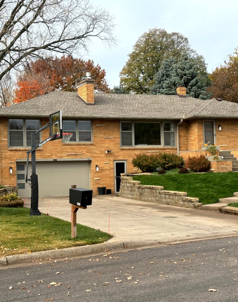 exterior orange stone and brick, weathered wood fiberglass roof, sherwin williams taupe tone on the garage door, windows, anad trim.  