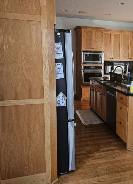 kitchen with golden oak wood cabinets and flooring, black raised island countertop with bar area, (2)