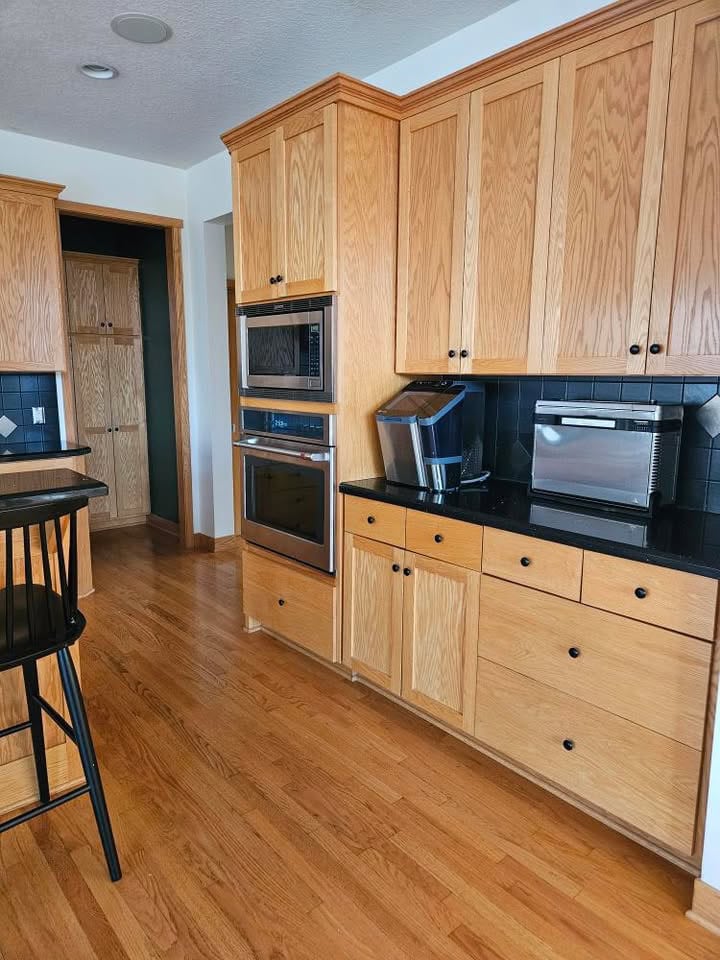 oak wood kitchen cabinets with golden oak floor, black countertop