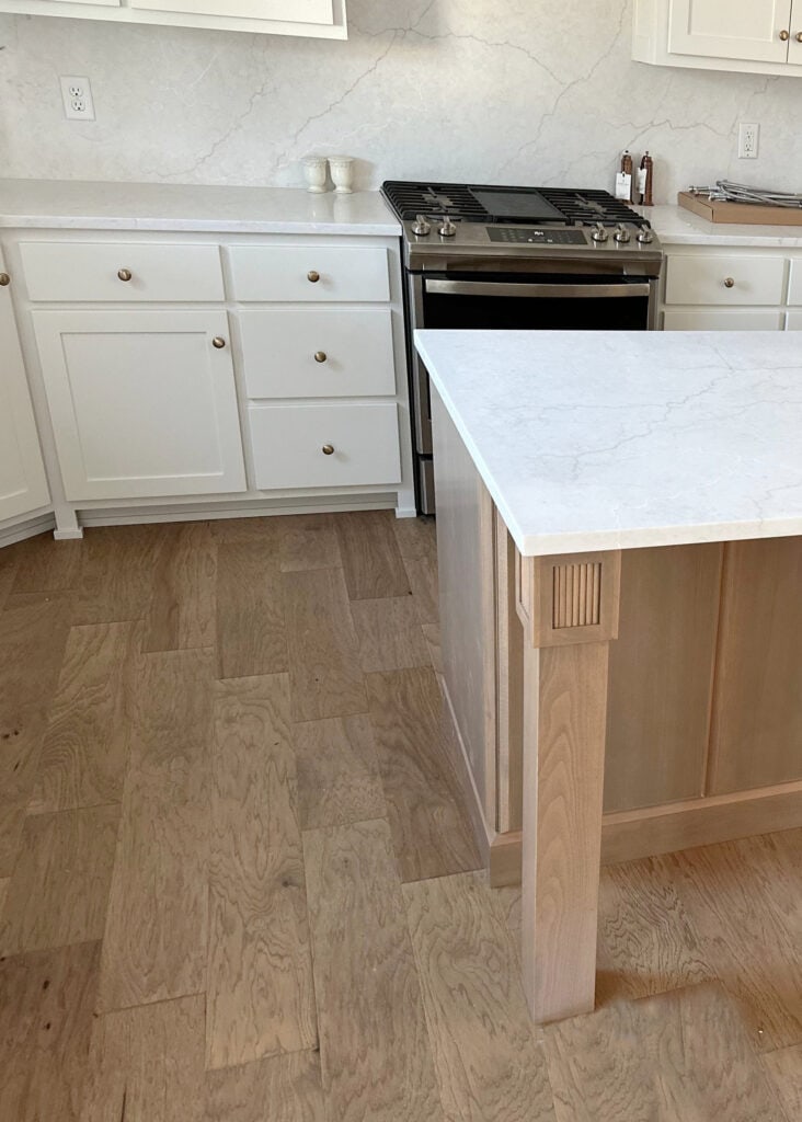off-white warm gray quartz countertop on island with wood, wood flooring, Sherwin Williams PUre White kitchen cabinets, gold hardware (1)