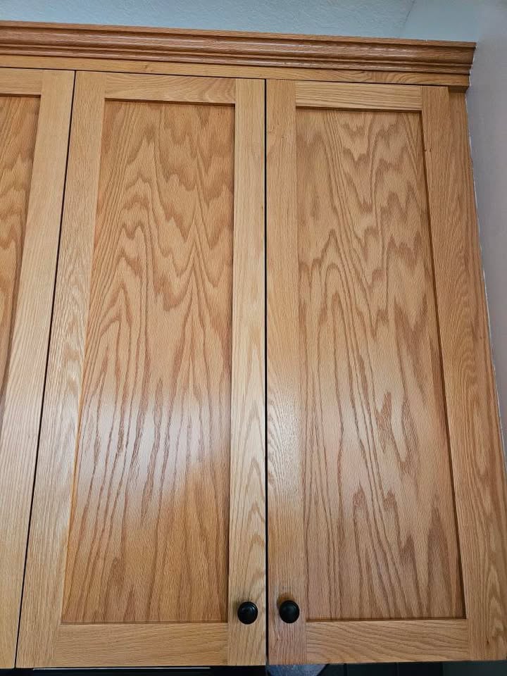 shaker style oak cabinet doors with grain and black hardware in kitchen