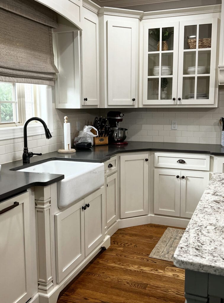 traditional kitchen with cream painted wood cabinets, matte or honed black granite countertop, oak wood floor, off-white subway tile backsplash