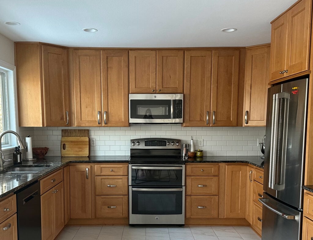 Ideas to update maple orange stain wood cabinets similiar to golden oak with older black granite countertop, warm white subway tile backsplash, tile floor, stainless appliances,
