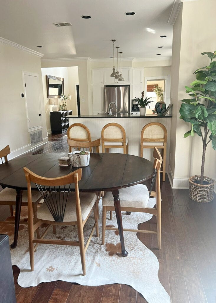 Sherwin Williams Casa Blanca in small open concept dining room, kitchen, white cabinets, dark wood floor, cream paint color, black granite, cowhide rug