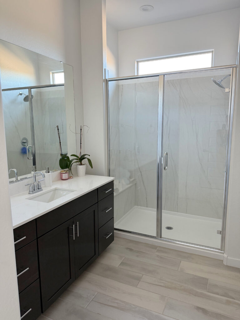 Sherwin Williams Etra White ensuite bathroom, dark wood vanity, white quartz, tile look wood floor, taupe pink tones, marble look shower walk in surround