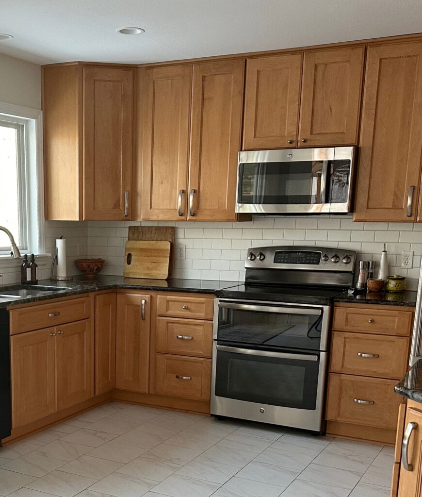 Update a wood kitchen with golden oak or orange maple cabinets, black granite countertop, warm white subway tile backsplash, stainless steel, tile floor