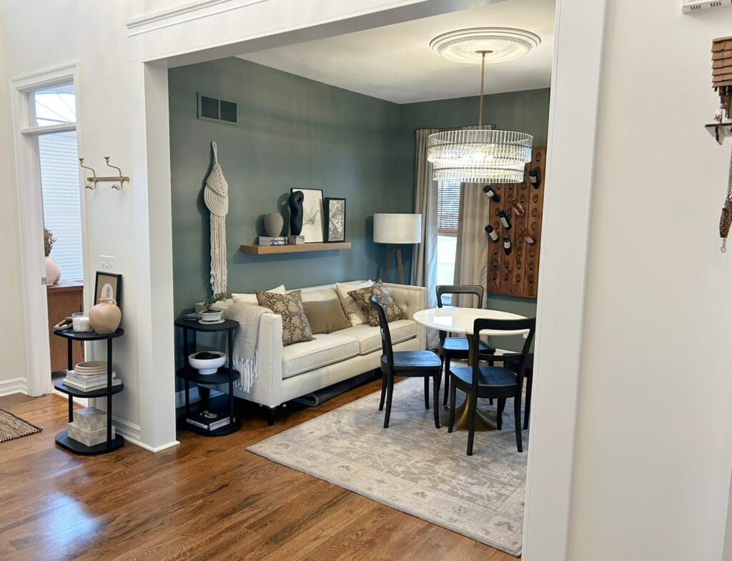 Benjamin Moore Chamois, White Dove trim, Sherwin Williams Retreat dark green paint color, den with sofa, marble round dining table, black chairs, home decor, dark oak wood floor