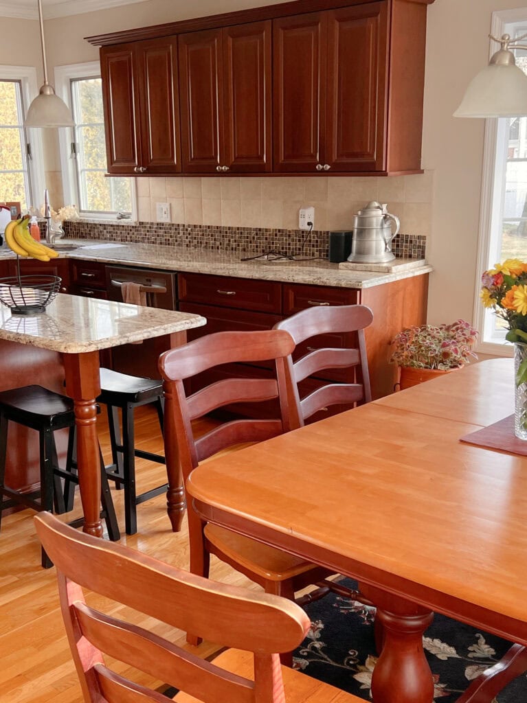 Cherry, red-stained wood maple cabinets, golden oak floor, granite countertop, beige travertine look tile backsplash in kitchen (1)