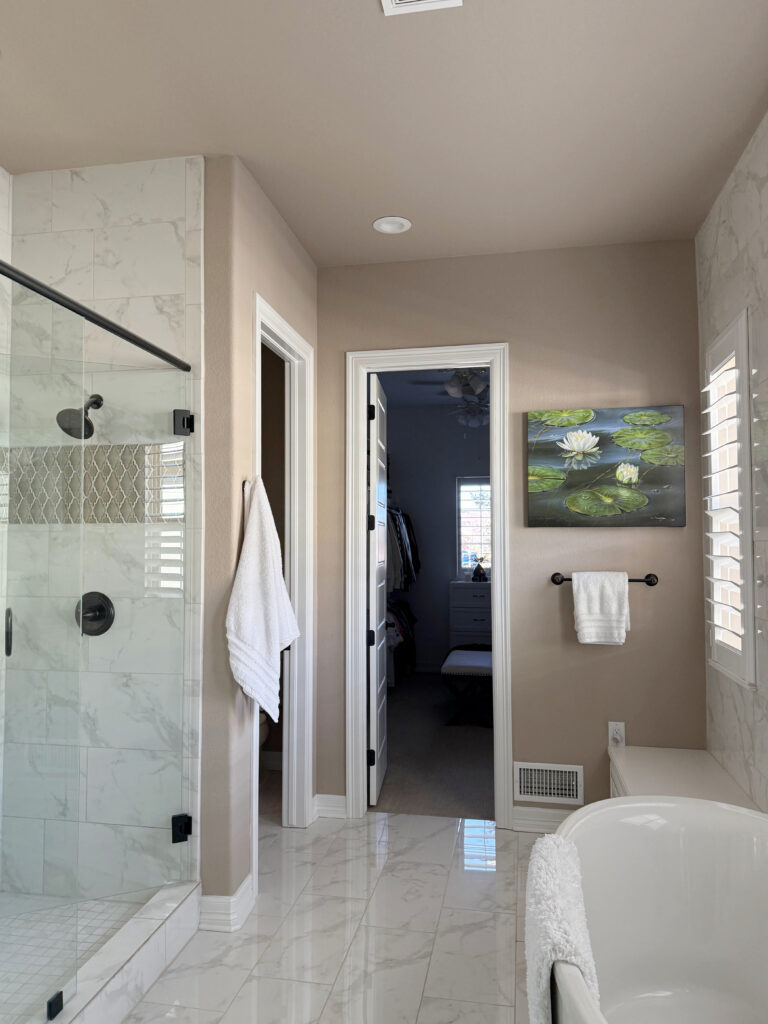 Ensuite bathroom with marble look tile floor and shower, accent mosaic tile. Sherwin Williams Balanced Beige walls and ceiling