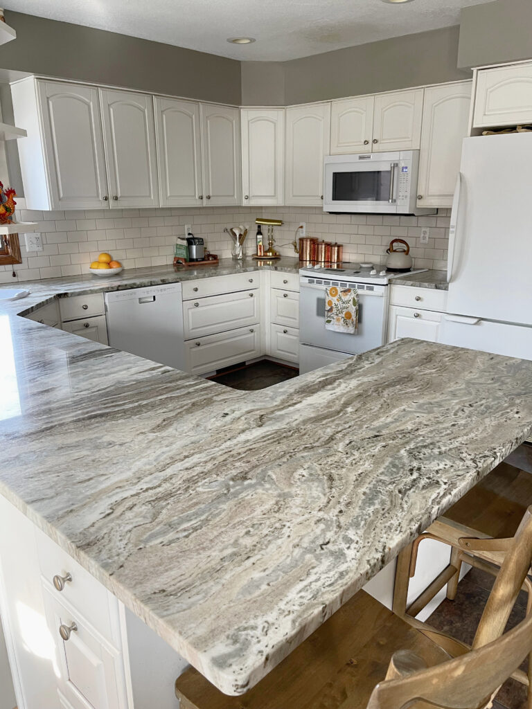 Fantasy Brown quartzite, Royal cream subway tile warm white cream cabinets, tile floor in kitchen, white appliances, greige walls