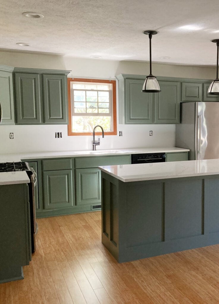 Kitchen with green painted wood cabinets, Benjamin Moore Chantilly Lace walls, Sherwin Williams Retreat, wood trim, white quartz countertop