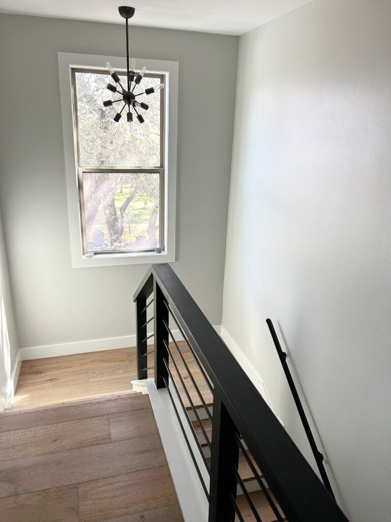 Sherwin Williams Guild Gray in staircase wit modern metal horizontal railings, wood floor, Extra White trim