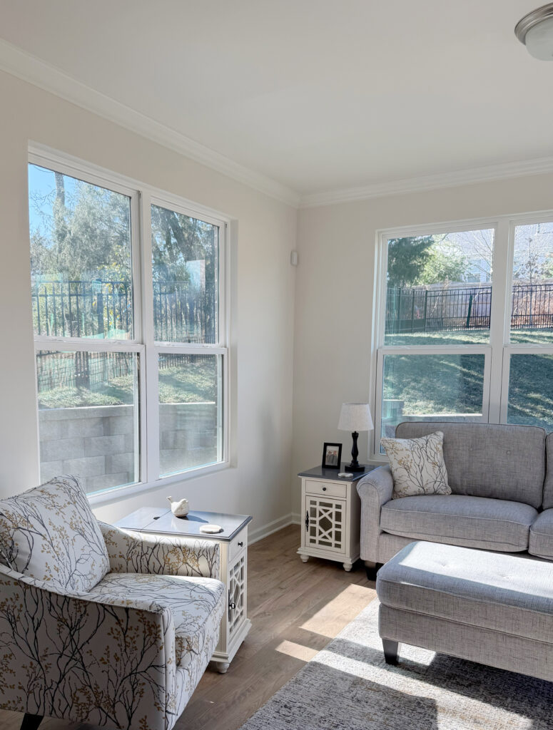 Sherwin Williams White Heron in den, sitting room with gray sofa, wood floor, white trim