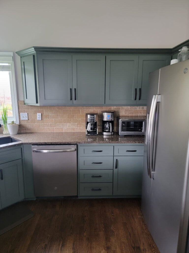 1990s Kitchen after paint, wood cabinets Sherwin Williams Pewter Green, granite countertop, travertine tile backsplash, stainless steel appliances, wood floor