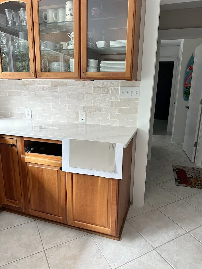 Backsplash tile similar to Cloe Bedrosian Zellige tile, Et Calacatta Gold white quartz countertop, taupe tile floor, cherry wood cabinets
