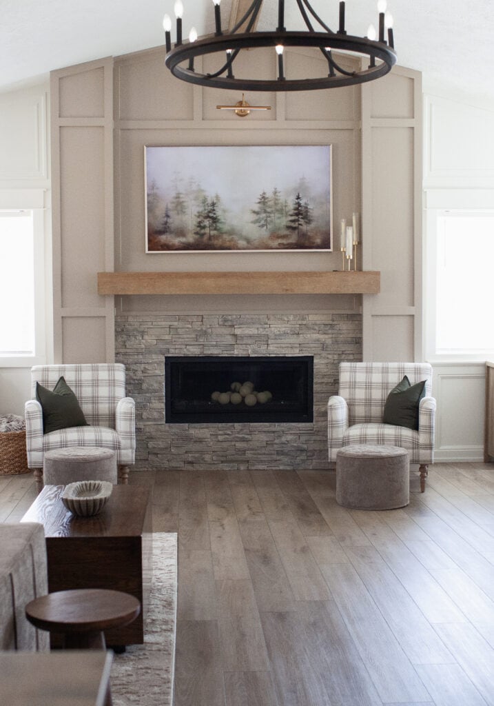 Fireplace update ideas, stacked stone in gray beige, wood mantel, moldings, trims added in Sherwin Williams Balanced Beige Graywash LVP flooring, accent chairs, Living room