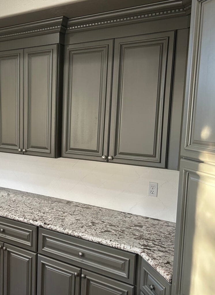 Granite countertops, dark red wood floor, painted tile backsplash. Sherwin Williams Porpoise greige cabinets, pewter hardware, DENTIL MOLDING
