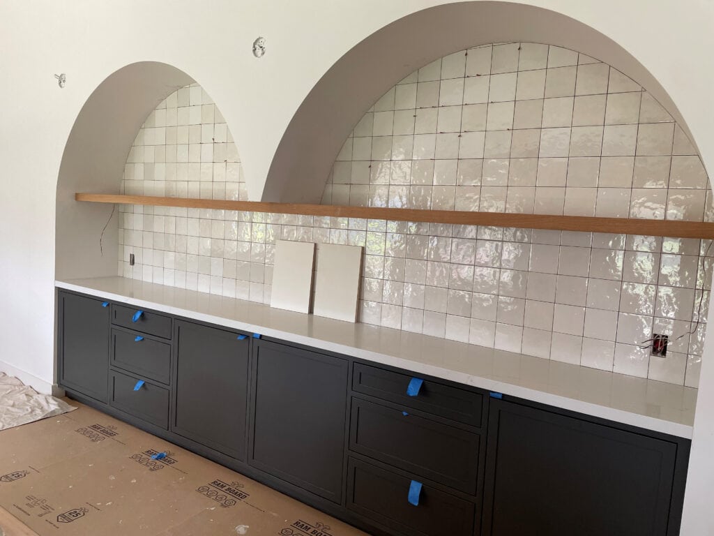 Home bar, built-in buffet with two drywall arches, wood floating shelve, square zellige tile, Sherwin Williams Iron ore, soft black cabinet color
