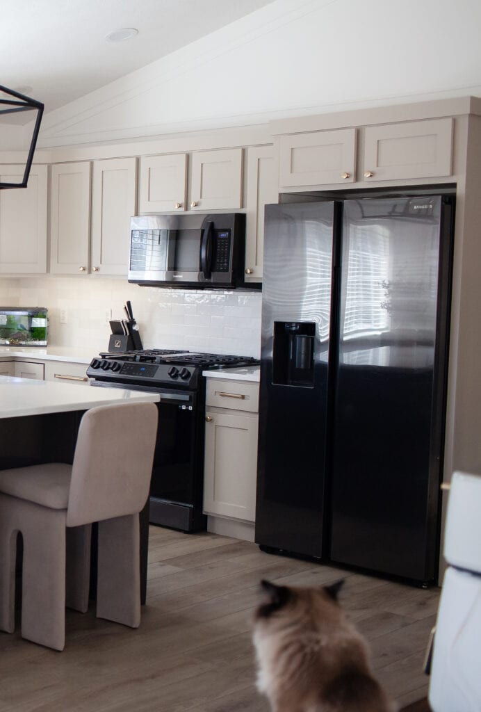 Kitchen wood cabinet update with painted Sherwin Williams Balanced Beige, Cold Foam white walls, black appliances, LVP floor, zellige tile backsplash