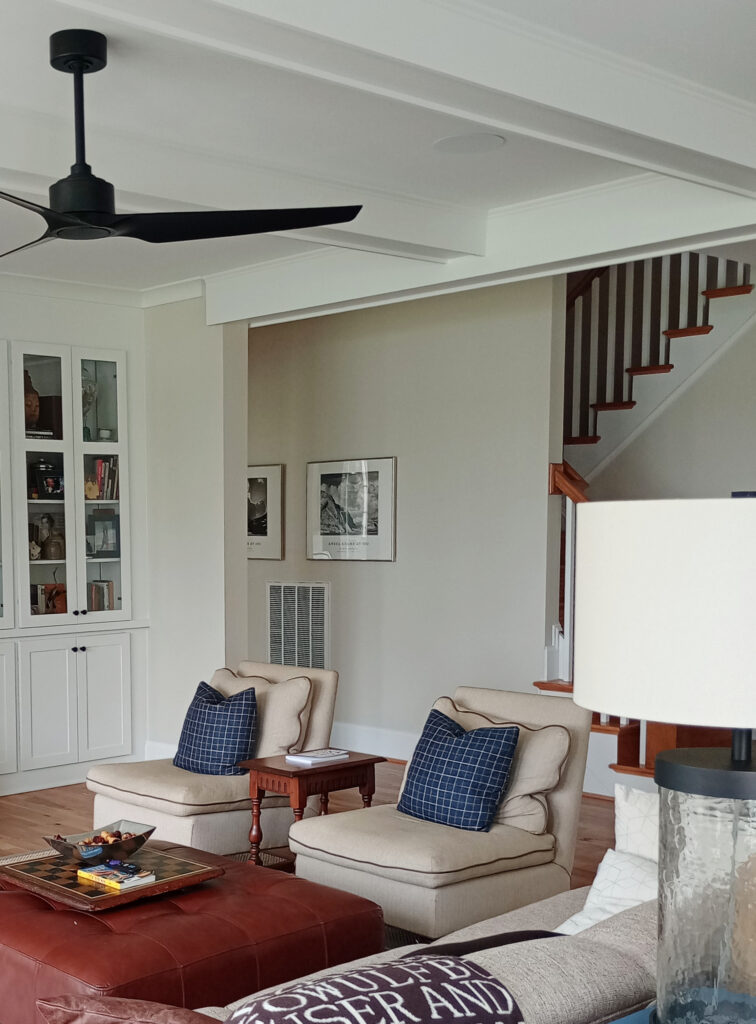 Living room walls painted Benjamin Moore Winds Breath, Pure White painted beam ceiling, built-ins, beige accent chairs, home decor
