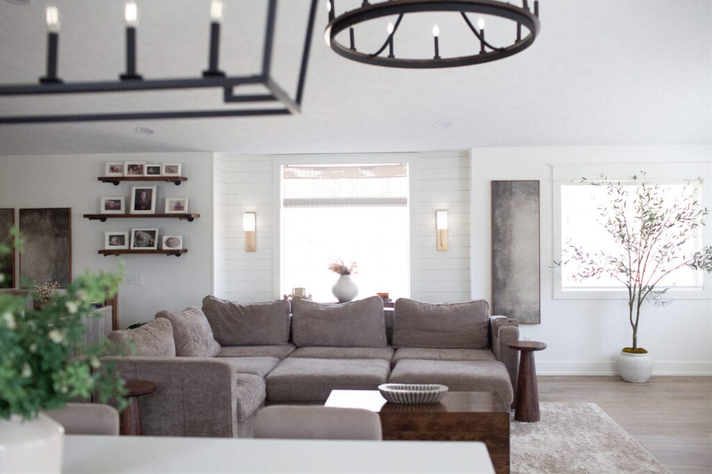 Open concept split level home, living room with recess in shiplap, taupe or greige sectional sofa, Cold Foam walls, warm white, wall light sconces beside windows, home decor