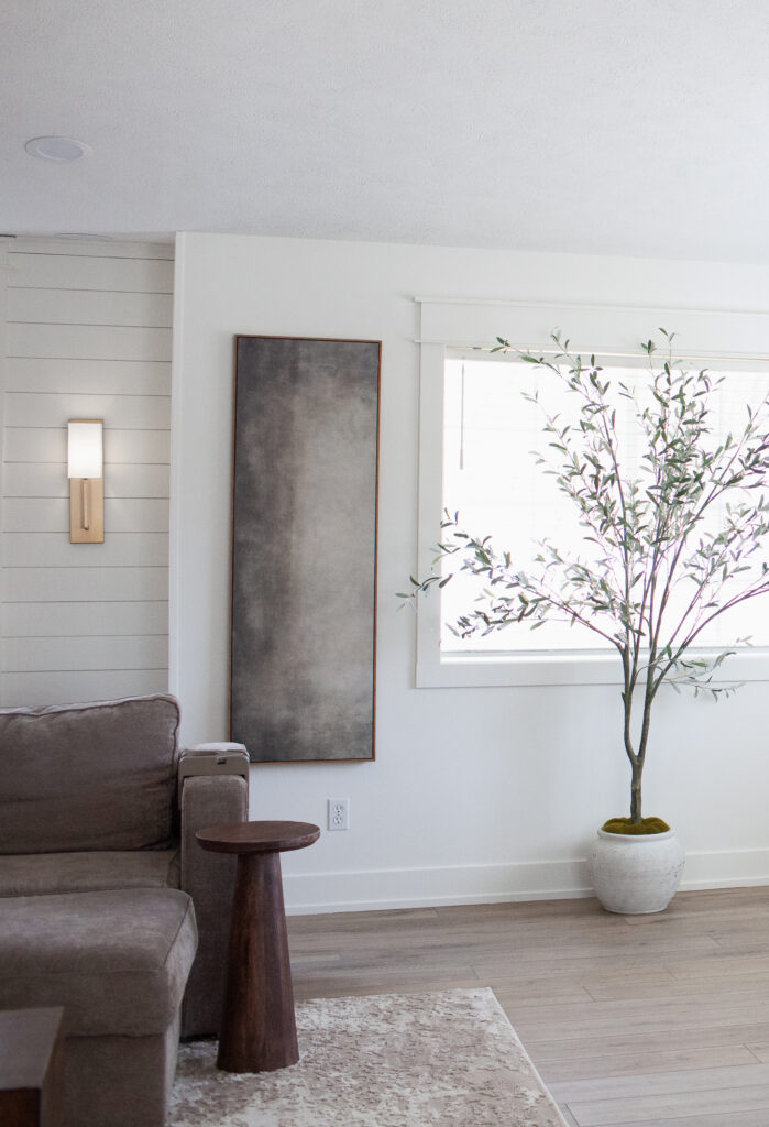 Sherwin Williams Cold Foam warm white walls, shiplap accent in alcove or niche with wall sconce, graywash wood look LVP floor, window and taupe sofa