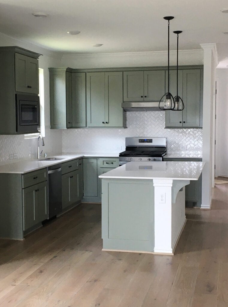 Sherwin Williams Evergreen Fog, best green painted cabinets, Kitchen, whitewash wood floor, island, herringbone white subway tile backsplash, black hardware, white quartz countertop