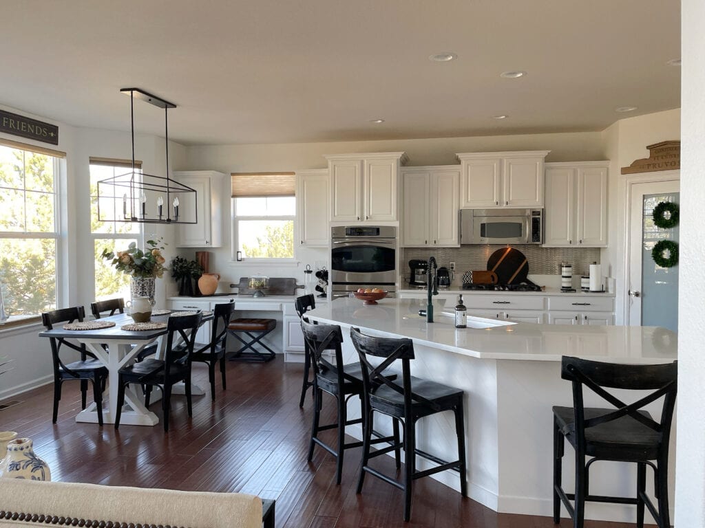 Sherwin Williams Pure White on painted kitchen cabinets and walls, dark red stain wood floor, white quartz countertop, black farmhouse modern chairs and stools, home decor
