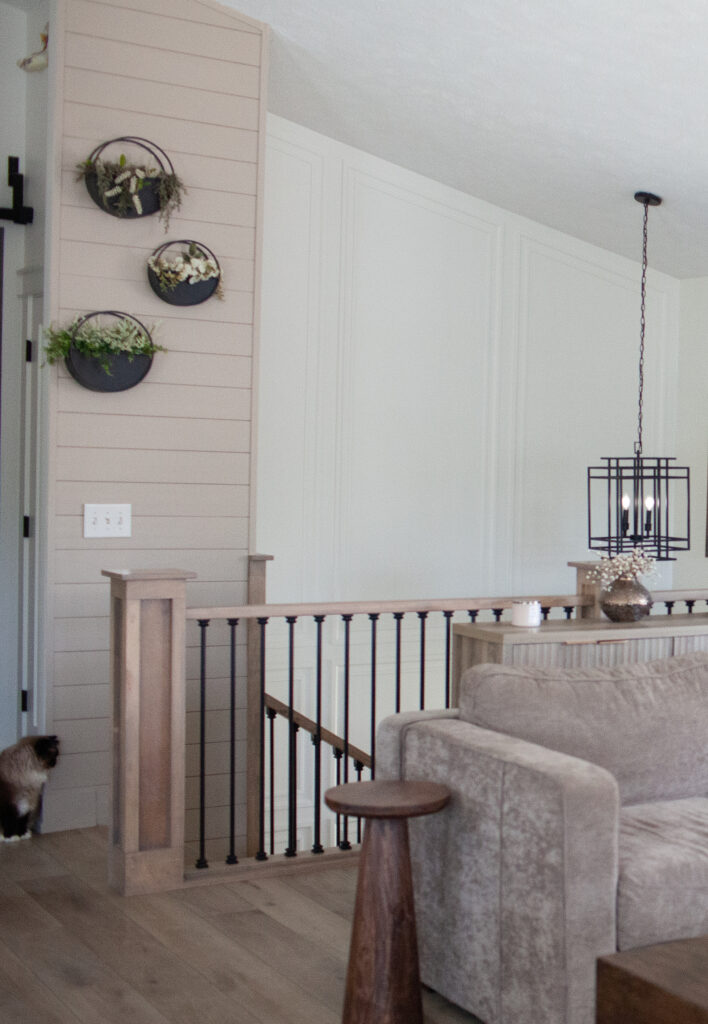 Staircase foyer in split level home, Sherwin Williams Balanced Beige shiplap accent wall, Cold Foam moldings on walls, black spindles, wood railing