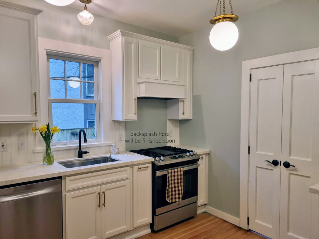 White kitchen cabinets, heritage older home, wood floor, white cabinets and trim, Sherwin Williams Sea Salt walls, beadboard backsplash
