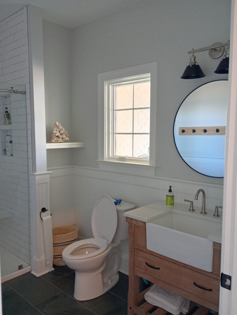 Wood and farmhouse sink style vanity in small bathroom, dark gray and black slate tile floor, Pure White beadboard, trim, Silverpointe on walls,