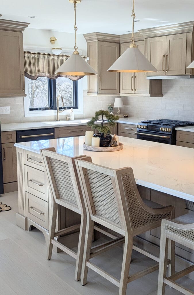 Zellige tile backsplash, whitewash wood floor, white quartz, Vicostone Misterio Gold, stained oak wood cabinets, ge matte black appliances, brushed brass hardware, wood counter stools