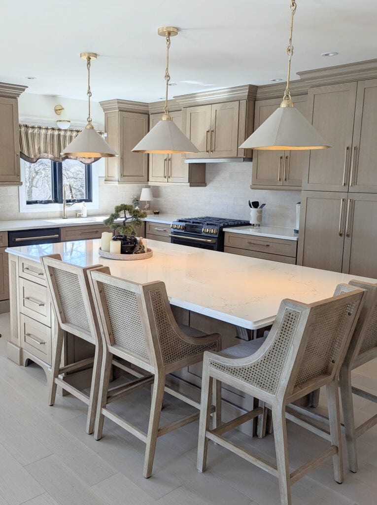 white washed wood floor and custom stained wood cabinets, island, stools, white quartz, vicostone Misterio Gold, ge matte black appliances, white pendan lights, zellige backsplash, Cheviot walls