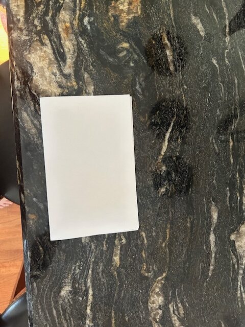 Cosmic Black with gold and white veining granite countertop update ideas with white paper for comparison