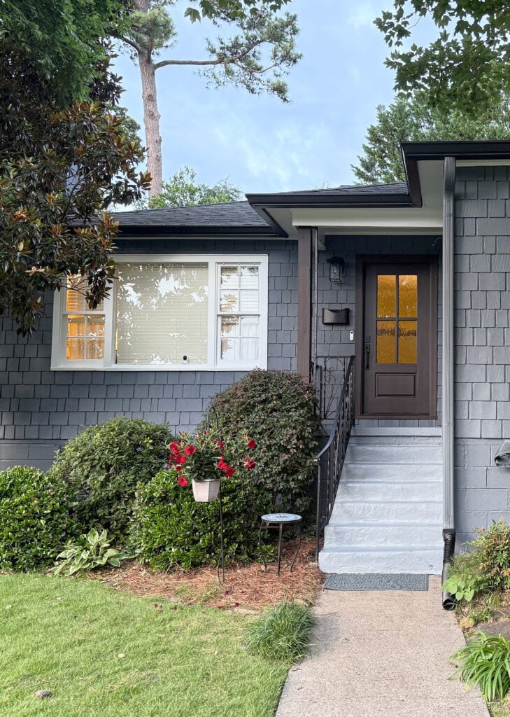 Sherwin Williams Gibraltar, dark blue-gray exterior shingles and siding, painted steps in Serious Gray, dark brown purple front door and beam, white windows, character home, cottage