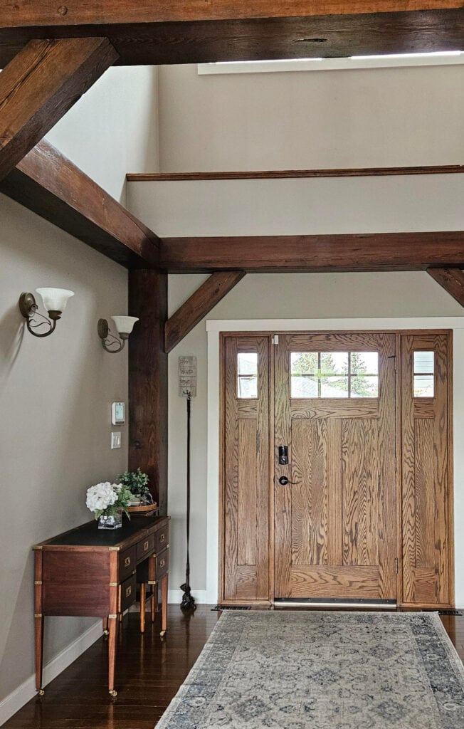 Benjamin Moore Smokey Taupe wood beams in 2 story entryway, oak front door, red wood stain.
