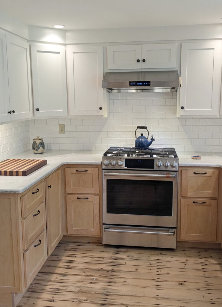 Emerstone Dynamic Gold quartz is a warm veining, warm white subway tile with maple wood lower cabinets in natural finish, original farmhouse floors, Sherwin Williams Alabaster upper cabinets