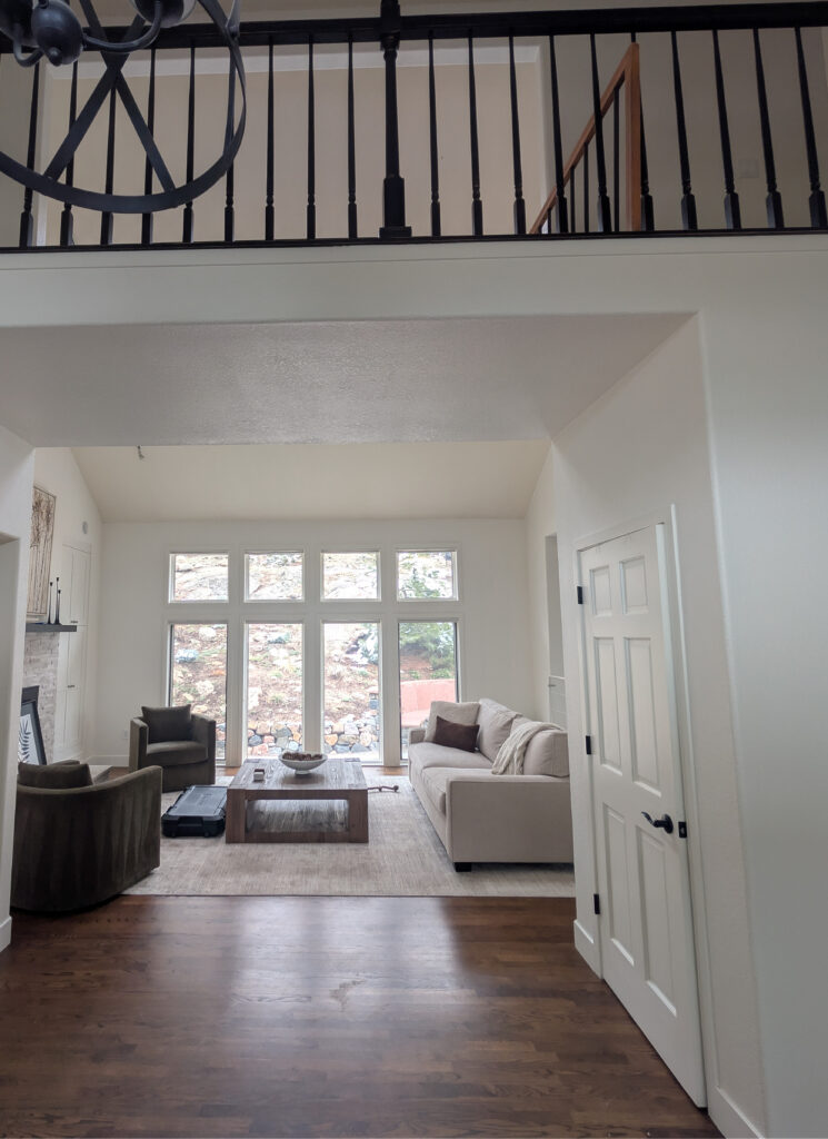 Sherwin Williams Alabaster, dark oak wood flooring, living room vaulted, neutral furniture, painted black stair railing